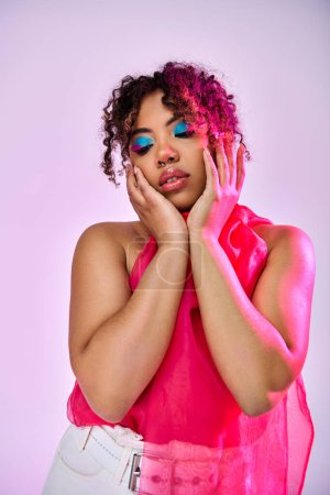 Photo for African American woman in a pink top, holding her face with her hands in contemplation. - Royalty Free Image
