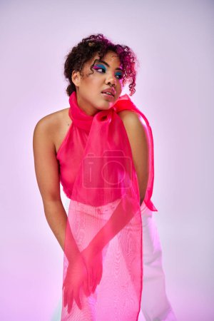 Téléchargez les photos : Femme afro-américaine pose gracieusement dans une robe rose et écharpe. - en image libre de droit
