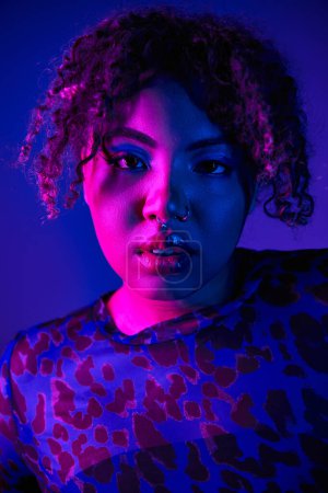 Photo for African American woman with curly hair in leopard print shirt posing on vibrant backdrop. - Royalty Free Image