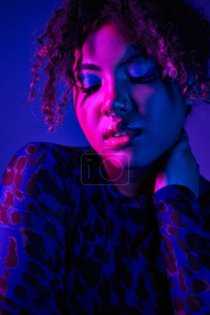 Téléchargez les photos : Beauté afro-américaine en chemise imprimé léopard, exhibant fard à paupières bleu captivant. - en image libre de droit