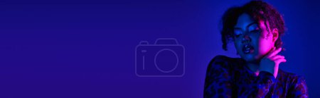 Téléchargez les photos : Une belle femme afro-américaine pose gracieusement sur un fond violet vibrant. - en image libre de droit