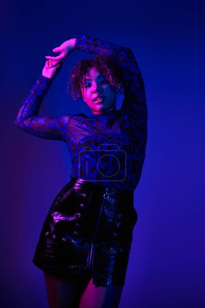 Téléchargez les photos : Beautiful African American woman striking a pose in vibrant black and purple attire. - en image libre de droit
