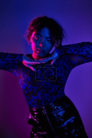 Téléchargez les photos : Une femme afro-américaine élégante posant activement dans une chemise imprimée léopard et une jupe en cuir. - en image libre de droit