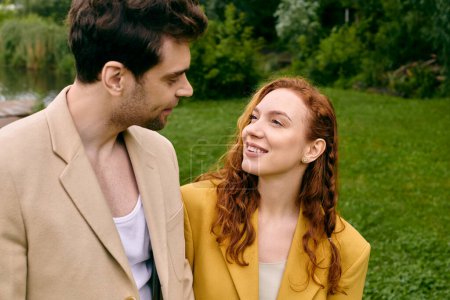 Téléchargez les photos : Un homme et une femme se tiennent côte à côte dans un parc verdoyant et luxuriant, profitant d'un rendez-vous romantique ensemble. - en image libre de droit