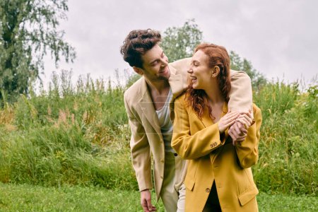 Téléchargez les photos : Un homme et une femme se tiennent tranquillement dans un champ verdoyant, se prélassant dans la beauté de la nature autour d'eux. - en image libre de droit