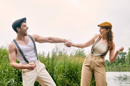 Téléchargez les photos : Un homme et une femme se tiennent la main passionnément par un plan d'eau serein dans un parc verdoyant, exprimant leur amour et leur profonde connexion. - en image libre de droit