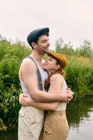 Ein Mann und eine Frau stehen anmutig zusammen an einem ruhigen Gewässer in einem üppig grünen Park und teilen einen romantischen Moment.