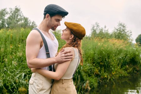 Foto de Un hombre y una mujer se paran cerca uno del otro en un parque verde, su conexión evidente en sus poses relajadas. - Imagen libre de derechos