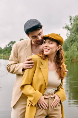Ein Mann und eine Frau, ein romantisches Paar, stehen ineinander verschlungen in der Nähe eines ruhigen Gewässers in einer friedlichen grünen Parklandschaft..