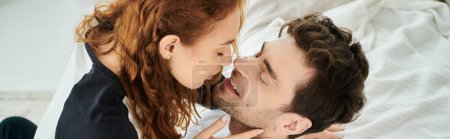 Téléchargez les photos : Un homme embrasse tendrement une femme sur la joue, exprimant amour et affection dans un cadre de chambre confortable. - en image libre de droit