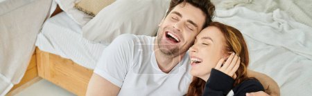 Un homme et une femme couchés sur un lit, partageant un moment de pure joie alors qu'ils rient ensemble.