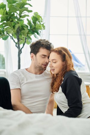 Téléchargez les photos : Un homme et une femme sont assis ensemble sur un lit confortable, profitant de l'autre compagnie - en image libre de droit