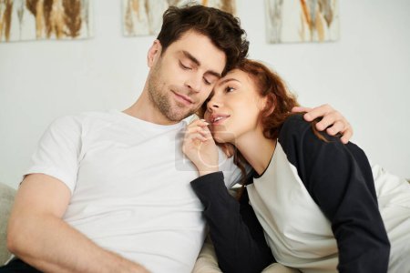 Un homme et une femme se prélassant confortablement sur un canapé, profitant mutuellement de la compagnie dans un cadre confortable.