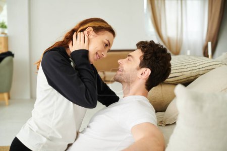 A man laying on a bed next to a woman, both relaxing and sharing a quiet moment together in their bedroom.