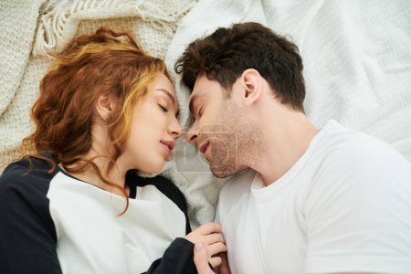 Téléchargez les photos : Un homme et une femme couchés côte à côte au lit, s'embrassant, partageant un moment paisible ensemble. - en image libre de droit