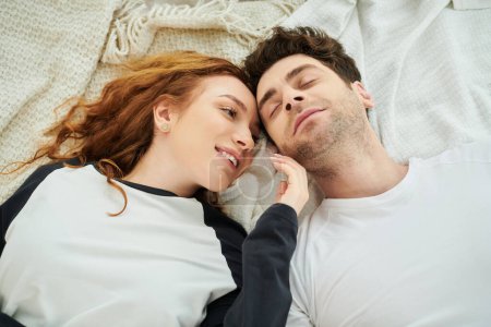 Foto de Un hombre y una mujer yacían acurrucados juntos en una cama, su conexión amorosa evidente en sus poses relajadas. - Imagen libre de derechos