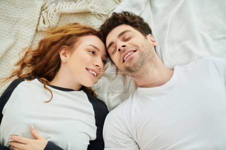 A man and a woman relax together on a bed in a cozy bedroom, enjoying each others company in a peaceful moment.