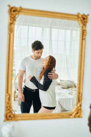 Ein Mann und eine Frau, die zusammen vor einem Spiegel stehen, ihre Spiegelungen betrachten und einen Moment der Zweisamkeit genießen.