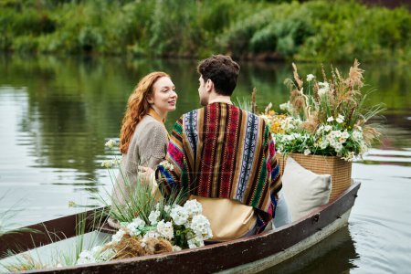 Ein Mann und eine Frau in Boho-Kleidung segeln in einem Boot, das von blühenden Blumen umgeben ist, und genießen ein romantisches Date in einem grünen Park.