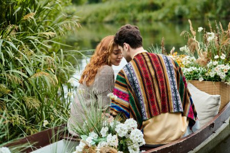 A man and woman dressed in boho style clothes drift in a boat adorned with flowers through a lush green park.