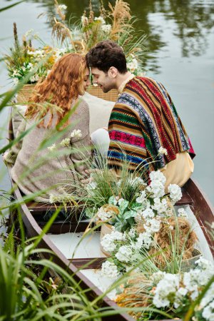 Téléchargez les photos : Un homme et une femme en vêtements de style boho assis paisiblement dans un bateau sur l'eau lors d'un rendez-vous romantique dans un parc verdoyant luxuriant. - en image libre de droit
