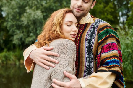 Photo for A man and a woman in boho attire embrace tenderly in a green park, exuding love and serenity in their romantic moment. - Royalty Free Image