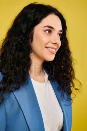 Brunette woman with curly hair showcases her emotions in a stylish blue jacket against a yellow backdrop.