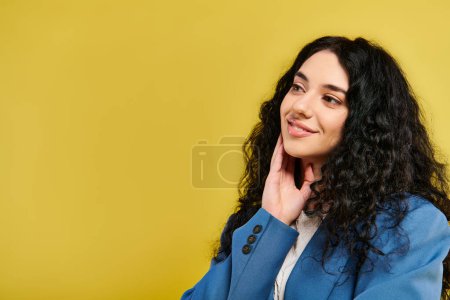 Foto de Una joven y elegante morena con el pelo rizado posando frente a un fondo amarillo vivo, mostrando varias emociones. - Imagen libre de derechos