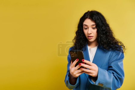 Una joven morena con chaqueta azul, cautivada por su celular.