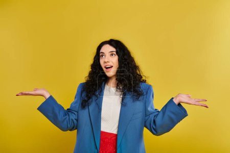 Photo for A young woman with curly hair, wearing a blue jacket, stretches out her hands, displaying a range of emotions. - Royalty Free Image