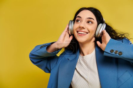 Mujer morena en chaqueta azul escuchando música a través de auriculares, exudando paz y relajación en un entorno de estudio amarillo.