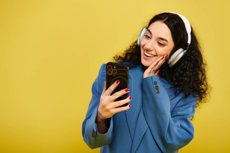 Una joven morena, con el pelo rizado, con auriculares, sosteniendo un teléfono celular, perdida en la música.