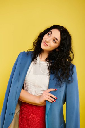 Photo for A young woman with curly hair poses in stylish attire in front of a vibrant yellow wall, exuding confidence and emotion. - Royalty Free Image