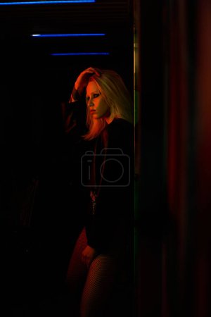 Eine Frau steht mit der Hand auf dem Kopf in einem schwach beleuchteten Raum