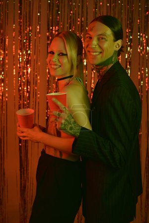 Foto de Un hombre y una mujer con atuendo casual se paran uno al lado del otro en un vibrante lugar de fiesta rave - Imagen libre de derechos