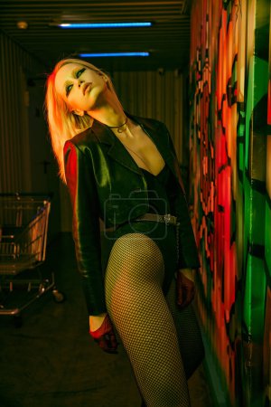 Woman in fishnet stockings leaning against a wall at a rave-party or nightclub