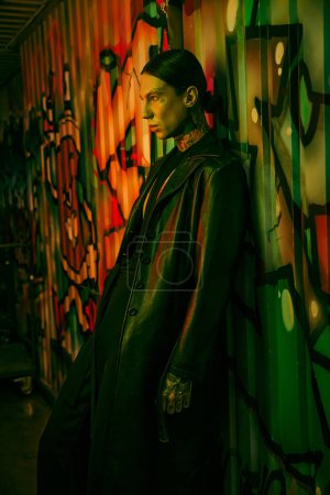 Foto de Un hombre al lado de una colorida pared cubierta de graffiti - Imagen libre de derechos