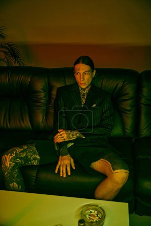 A man dressed in a suit is seated on a couch