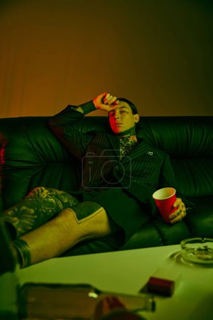 A man sitting on a couch, holding a cup of coffee