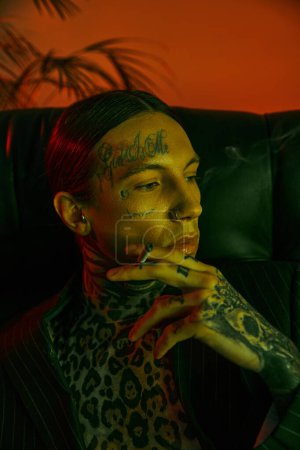 Téléchargez les photos : Un homme tatoué sur le visage fumant une cigarette - en image libre de droit