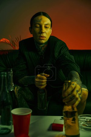 Un homme assis à une table avec une bouteille d'alcool