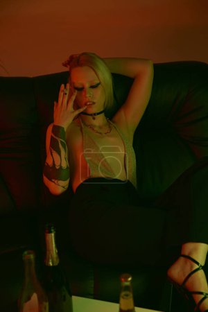 Mujer sentada en un sofá, fumando cigarrillo en una fiesta o discoteca