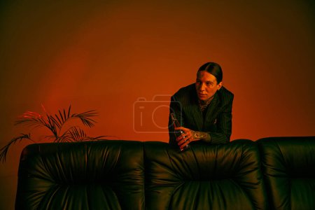A man casually sits on a black couch