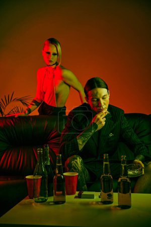 Un hombre está sentado en un sofá junto a una mujer en una fiesta de rave o un club nocturno de rave