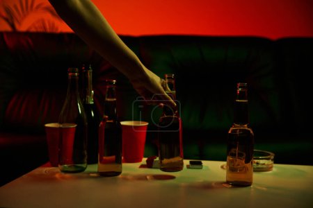 Eine Person greift bei einer Rave-Party nach einer Flasche Alkohol