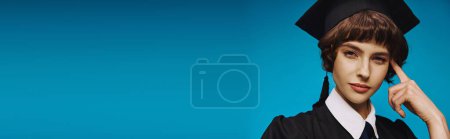Photo for Banner of pensive college girl wearing black graduation gown and academic cap on blue backdrop - Royalty Free Image
