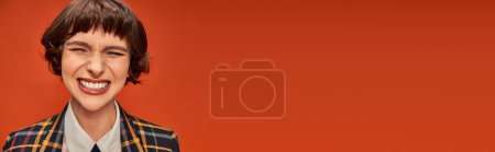 Téléchargez les photos : Joyeuse étudiante avec un sourire rayonnant montrant ses dents blanches sur fond orange vibrant, bannière - en image libre de droit