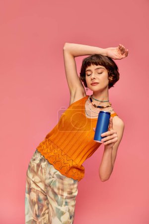 Photo for Pretty young woman with short brunette hair holding soda can while posing on pink, summer beverage - Royalty Free Image