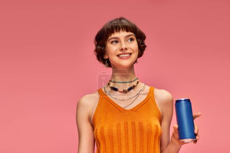 Photo for Joyful young woman with short brunette hair holding soda can while posing on pink, summer beverage - Royalty Free Image