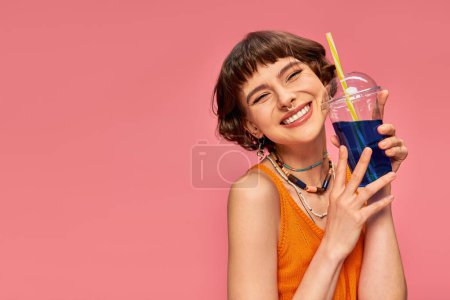 Photo for Cheerful young woman with short brunette hair posing with refreshing summer cocktail on pink - Royalty Free Image